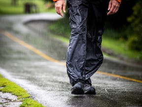 A man walks along the Rideau River Eastern Pathway in Riviera Park on a wet day.