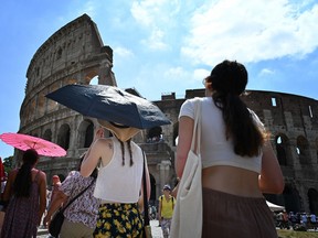 Tourists shelter from the sun with umbrellas near the Colosseum on July 14, as Italy is hit by a heatwave.