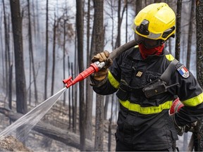 This June 28, 2023, image released by the Société De Protection Des Fôrets (SOPFEU) on June 30, 2023, shows a French firefighter assisting with wildfires at Lac Larouche.