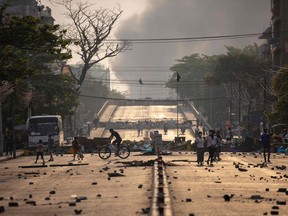 (FILES) People walk past makeshift barricades set up by protesters to block a road during demonstrations against the military coup in Yangon on March 15, 2021. Myanmar's National Defence and Security Council agreed July 31, 2023 to extend the country's state of emergency by six months, state media said, likely delaying elections the junta had pledged to hold by August. (Photo by AFP)