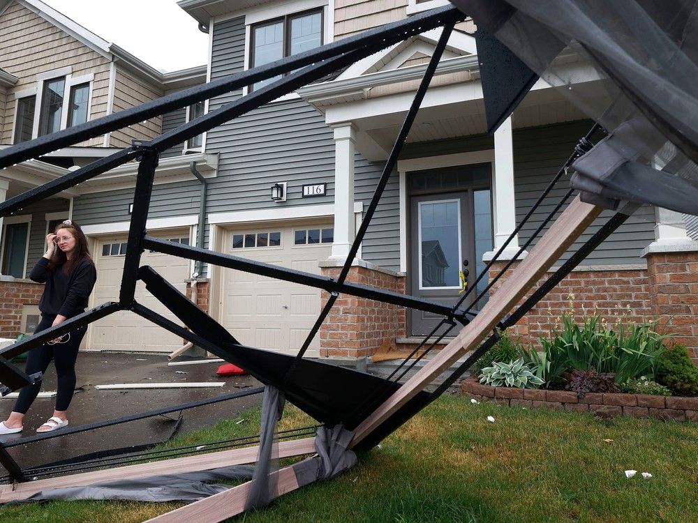 Families go Corrine Horan checks out the damage outside her home near Merak Park after a tornado rips through Barrhaven