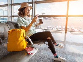 Happy asian woman waiting for her airplane in airport with passport and baggage. Vacation and journey concept