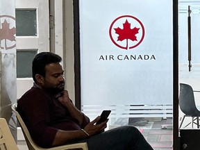 A man checks his mobile as he sits outside an Air Canada regional office in New Delhi on Sept. 20, 2023.