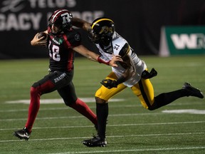 Hamilton Tiger-Cats linebacker Simoni Lawrence pushes Ottawa Redblacks quarterback Dustin Crum out of bounds as he runs the ball.