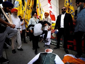 People deface a placard depicting Indian prime minister Narendra Modi during a Sikh rally outside the Indian consulate in Toronto to raise awareness for the Indian government's alleged involvement in the killing of Sikh separatist Hardeep Singh Nijjar in British Columbia on September 25, 2023.