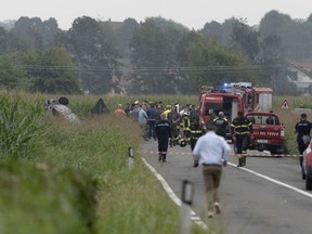 Firefighters seal off the area where an aircraft of the Italian acrobatic air team the Frecce Tricolori crashed, burnt car visible on the left