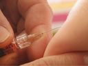 A children's doctor injects a vaccine against measles, rubella, mumps and chicken pox in this file photo.