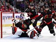 Ottawa Senators netminder Mads Sogaard down on the ice, centre Mark Kastelic (12) and defenceman Jacob Larsson