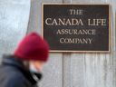 A pedestrian passes signage for The Canada Life Assurance Company building in Toronto on Tuesday, March 29, 2022.