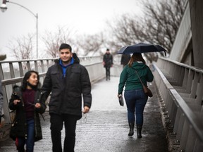 Pedestrians cross the Flora Footbridge near Lansdowne Park on a drizzly and damp day in Ottawa, Saturday, March 19, 2022.