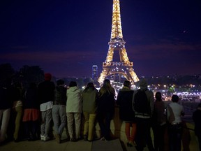 FILE - Tourists look at the illuminated Eiffel Tower in Paris, on June 13, 2013. A culinary issue erupted as the European Parliament prepares to vote on Wednesday, Nov. 22, 2023, on a proposal about packaging waste. Some French cheese producers feared that its language would mean their delectable, pungent Camembert will no longer be encased in wooden boxes.