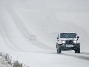 A vehicle travels a long a snow covered Highway 22 in Alberta