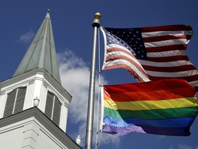 A rainbow flag flies along with the U.S. flag in front of the Asbury United Methodist Church in Prairie Village, Kan.
