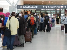 People line up before entering the security zone at Pearson International Airport in Toronto on Friday, August 5, 2022. A full tourism recovery is not expected until next year, Destination Canada says.