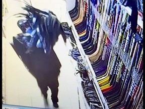 A person carrying $38,000 worth of hockey sticks and hockey gloves during a theft from the Cataraqui Canadian Tire in Kingston on Jan. 16, 2024.
