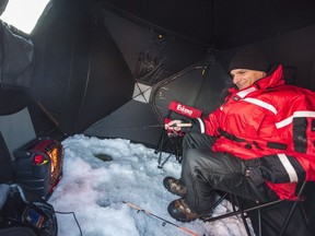 A fisherman warms up near a space heater inside his fishing shelter on the Bay of Quinte near Point Anne, Ont. Health Canada is considering banning some indoor electric space heaters.
