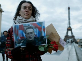 Demonstrator holding Navalny portrait near the Eiffel Tower in Paris