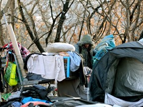 A resident gathers his belongings as police and city crews clear homeless encampments between Jasper Avenue and Dawson Park, in Edmonton on Jan. 2, 2024.