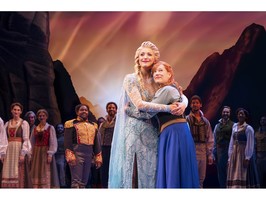 The actors playing princesses Elsa and Anna embrace during a scene from the Disney musical Frozen