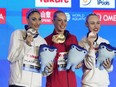 Gold medallist Jacqueline Simoneau of Canada, centre, silver medallist Evangelia Platanioti, of Greece, and bronze medallist Vasilina Khandoshka, a competitor from Belarus, pose for a photo during the medal ceremony for the women's solo free final of artistic swimming at the World Aquatics Championships in Doha, Qatar, Tuesday, Feb. 6, 2024.
