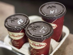 Restaurant Brands International Inc. reported its fourth-quarter net income more than doubled compared with a year ago. Cups of coffee sit on a counter in a Tim Hortons outlet in Oakville, Ont. on Monday September 16, 2013.