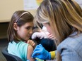 File photo: A nine-year-old rolls up her sleeve for a vaccination at a clinic in Portland, Ore.