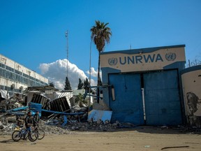 People walk past the damaged Gaza City headquarters of the United Nations Relief and Works Agency for Palestine Refugees (UNRWA) on February 15, 2024.