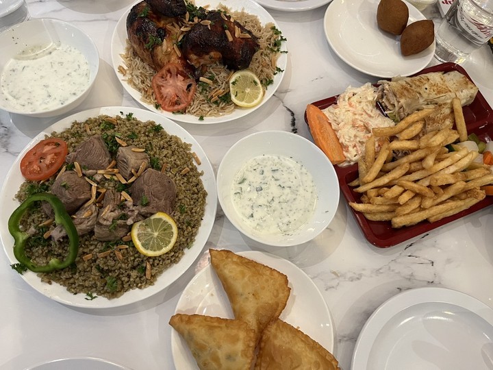  An array of dishes, including, from left to right, lamb on freekeh, chicken on kabsa rice, and saj chicken sandwich meal at Royal Rooster Shawarma