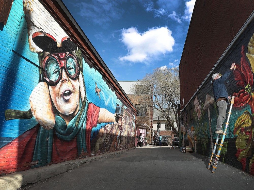 Artist Pat Buck paints a mural in the Glebe in 2021. Ottawa has more than 300 outdoor public murals, but that pales in comparison to many cities.
