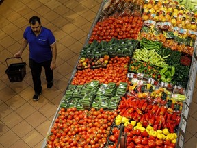 A shopper walks past produce at a grocery store
