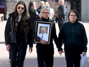 Franco Micucci's widow, Shirlene Byne, clutches a picture of her late husband as she leaves the Elgin Street courthouse Thursday with daughters Daisy Micucci, right, and Nadya Byne, left. The family was in attendance for the sentencing hearing of Tevon Bacquain.