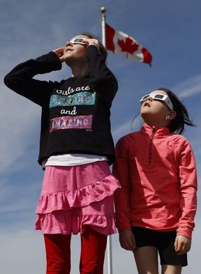 Families and friends take in the eclipse at Crysler's Farm outside Cornwall Monday.