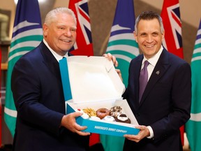 Ontario Premier Doug Ford and Ottawa Mayor Mark Sutcliffe open a box of Maverick's Donuts