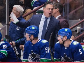 Former Vancouver Canucks head coach Travis Green stands on the bench.