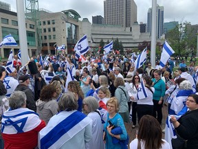 People dressed in blue and white and waving Israeli flags, gathered in the plaza at Ottawa city hall May 14 to commemorate Israel's independence, while pro-Palestinian protesters chanted in the background.