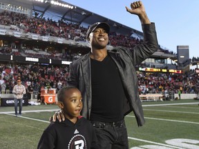 Former Ottawa Redblacks quarterback Henry Burris walks with his son during a ceremony honouring his career in 2017.