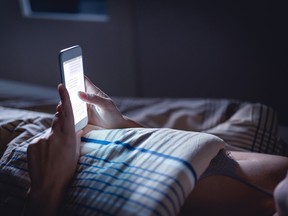 Woman in bed checks cellphone