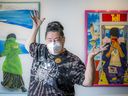 Laura Margita, curator and director  at Gallery 101 poses with a mask on in front of the Consumed Consequences exhibit by artist Dana Edmonds.
