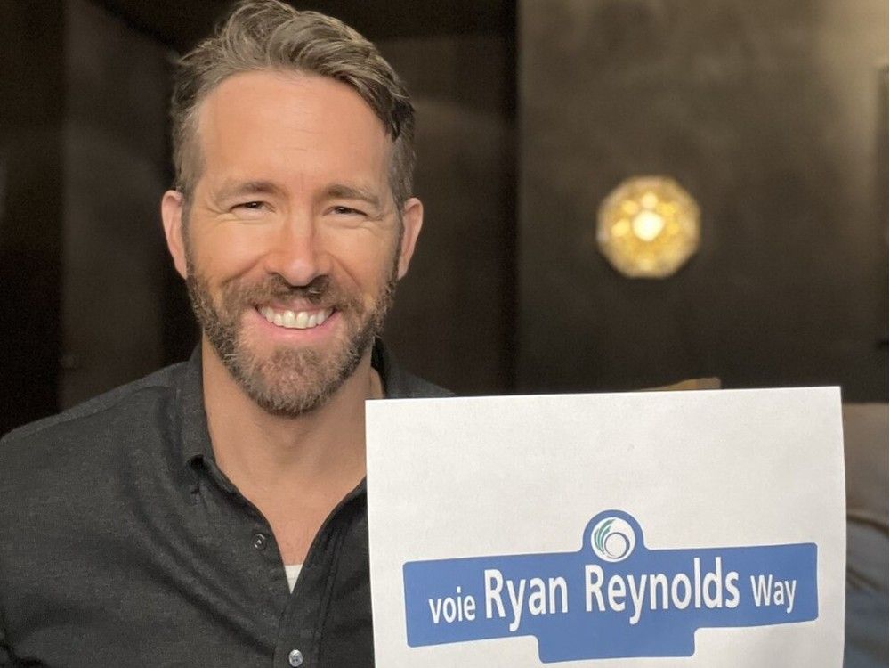 Ryan Reynolds holds up a mock-up of the Ottawa street sign tht now bears his name.
