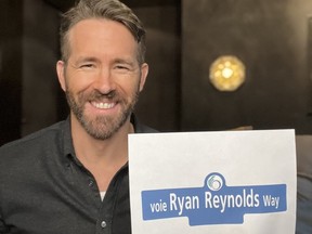 Ryan Reynolds holds a mock-up of the Ottawa street sign bearing his name