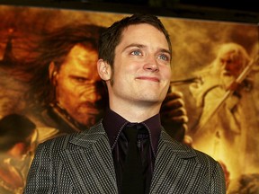 Elijah Wood stands in front of an LotR post with Aragorn (Viggo Mortenson) and Gandalf ( Ian McKellen).