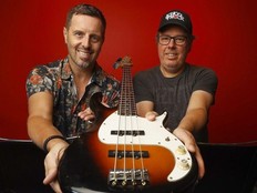 Two people hold up a bass guitar.