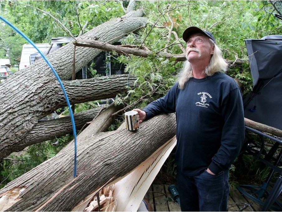 Bill Peterson surveys tree damage on the deck of his trail on Bass Lake, near Rideau Ferry, on Thursday, July 25, the day after a tornado hit.