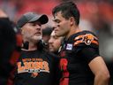 B.C. Lions head coach Rick Campbell, left, speaks to quarterback Nathan Rourke on the sideline during a game.