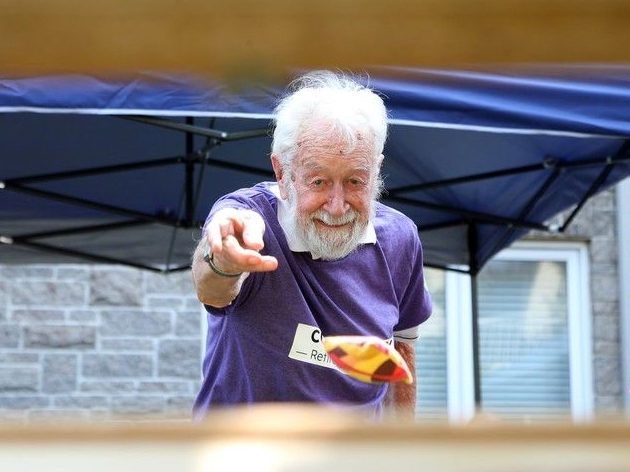  phil stevens, 94, can be seen through one of the bean bag toss openings at the event.