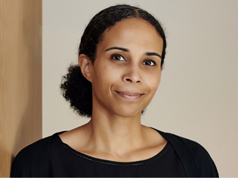 Someone wearing a black shirt in front of a beige wall