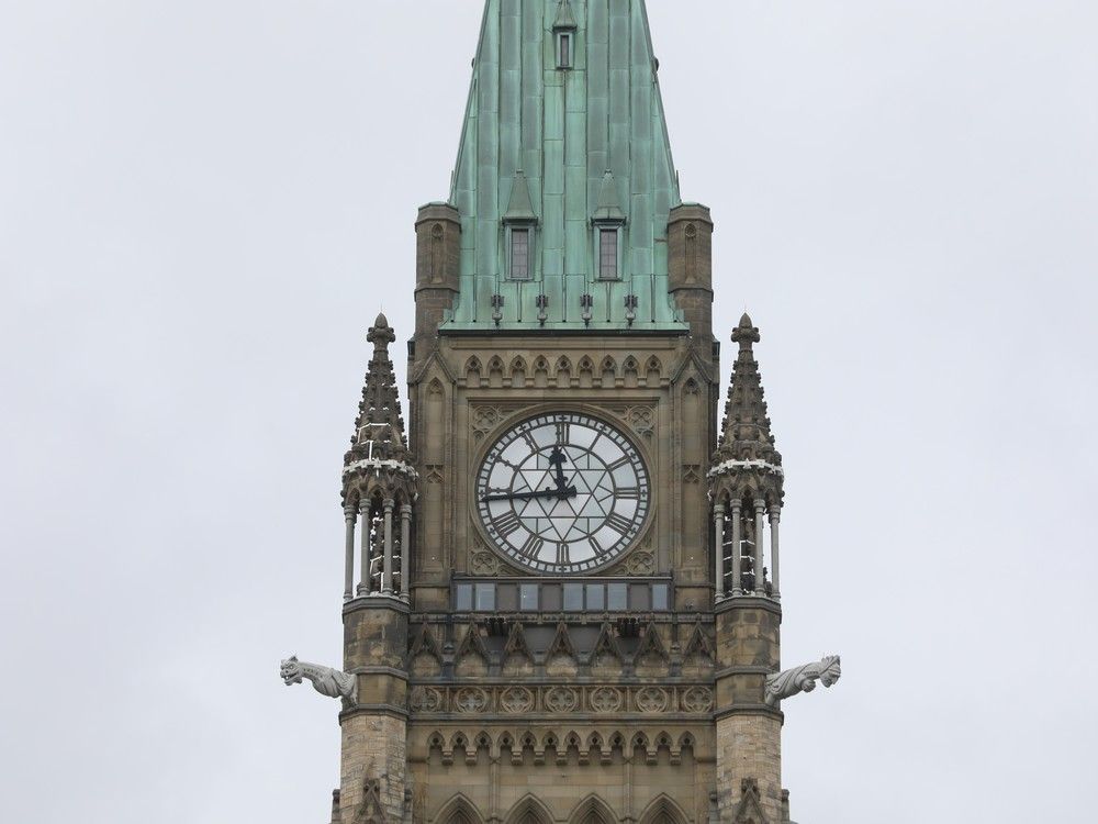 A close-up of the clock tower with its gargoylse and green copper roof