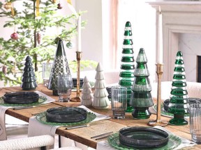 This modern rustic tabletop features decorative trees, brass candlesticks and coloured glass plates.