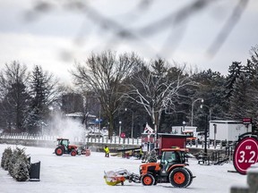 Small tractors clear snow off of the frozen-over Rideau Canal