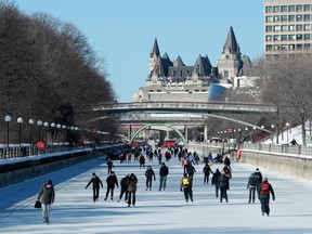 People skate on the Rideau Canal Skateway with the Chateau Fairmont Laurier in the backgorund